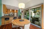 This modern kitchen and dining area features sleek, light wood cabinetry and a convenient breakfast bar with seating.