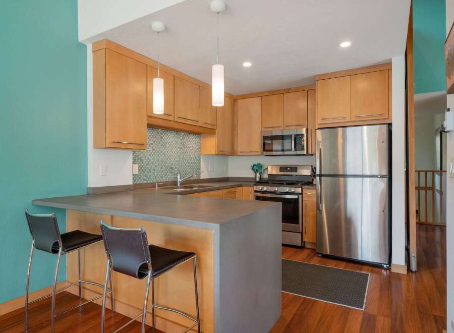 Discover this modern kitchen featuring sleek stainless steel appliances, including a refrigerator and microwave, complemented by warm wood cabinetry.