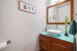 This modern bathroom features a sleek vanity with a vibrant turquoise countertop, topped with a stylish vessel sink and a polished chrome faucet.