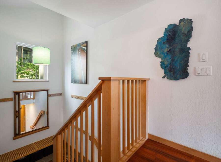 Ascend to the upper levels of this home via a beautifully crafted wooden staircase, bathed in natural light from a nearby window.