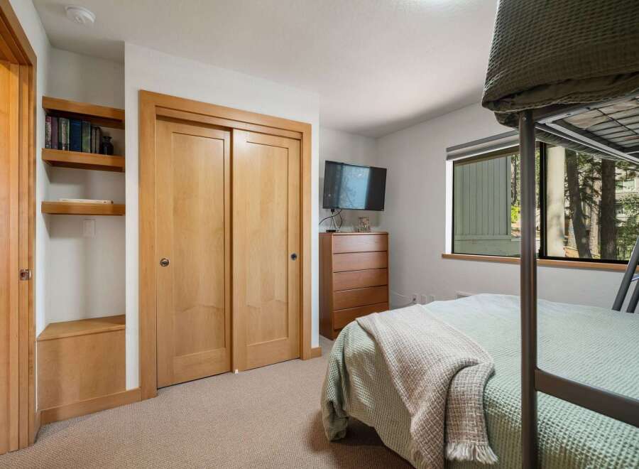 This cozy bedroom features a convenient built-in closet with sliding doors and open shelving for storage and display.