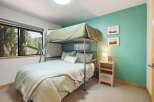 This charming bedroom features a space-saving bunk bed with a lower full-size bed and an upper twin-size bed, perfect for families or guests.