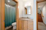 This modern bathroom features a sleek vanity with a granite countertop and ample storage, complemented by a stylish mirror and lighting.