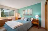 Experience serene lake views from this charming bedroom, featuring a comfortable queen-size bed adorned with a plush white throw.