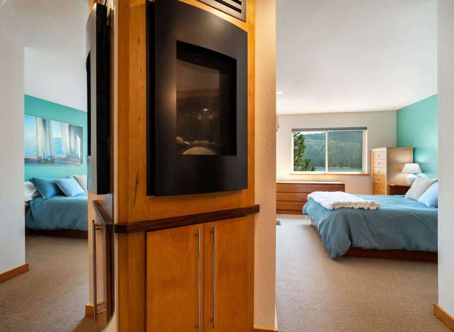 Experience serene living in this beautifully appointed bedroom, featuring a modern fireplace and a calming turquoise accent wall.
