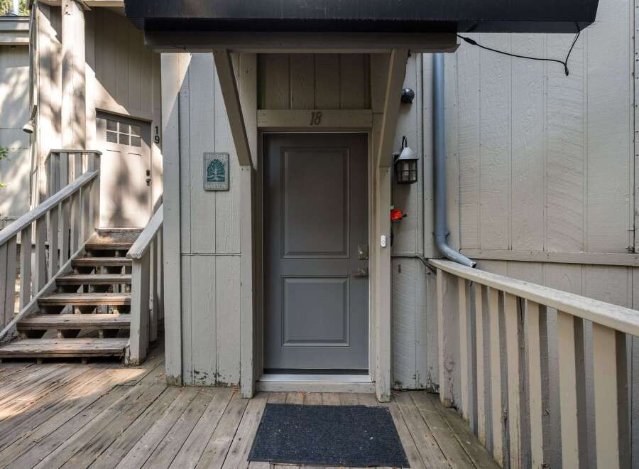 Welcome to this charming property featuring a welcoming entrance with a sturdy wooden deck and stairs leading to a private front door.
