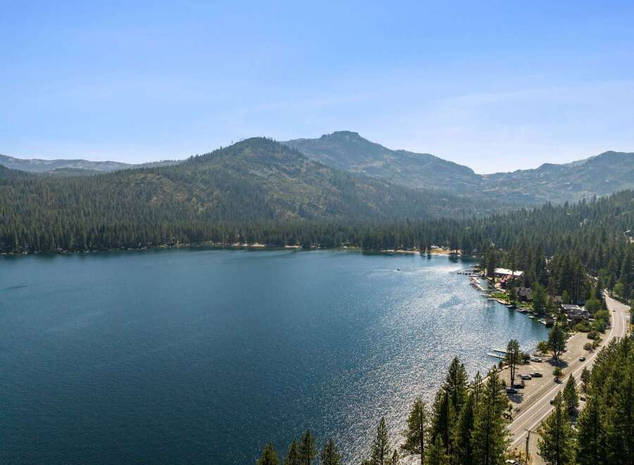 Experience the ultimate lakeside lifestyle with this stunning property offering breathtaking views of a pristine blue lake surrounded by lush green forests and majestic mountains.