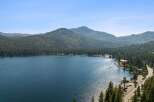 Experience the ultimate lakeside lifestyle with this stunning property offering breathtaking views of a pristine blue lake surrounded by lush green forests and majestic mountains.