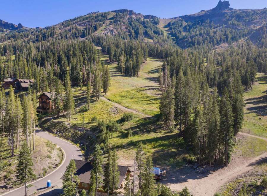 Nestled amidst a dense pine forest, this property offers a serene mountain retreat with stunning views of a ski slope and rugged peaks.