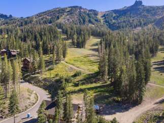 Nestled amidst a dense pine forest, this property offers a serene mountain retreat with stunning views of a ski slope and rugged peaks.