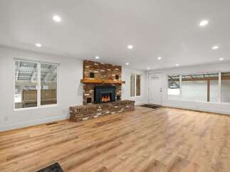 Experience cozy living in this beautifully renovated home featuring a stunning brick fireplace as the centerpiece of the spacious living area.