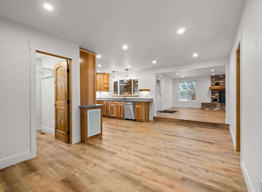 Discover this beautifully renovated home featuring a modern kitchen with ample wood cabinetry and stainless steel appliances, seamlessly flowing into a spacious living area.