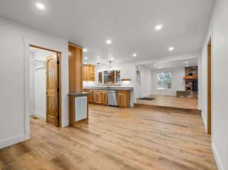 Discover this beautifully renovated home featuring a modern kitchen with ample wood cabinetry and stainless steel appliances, seamlessly flowing into a spacious living area.