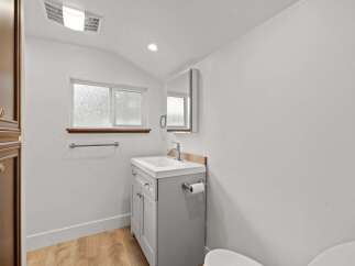 This bright and airy bathroom features a modern gray vanity with a white countertop and a sleek chrome faucet.