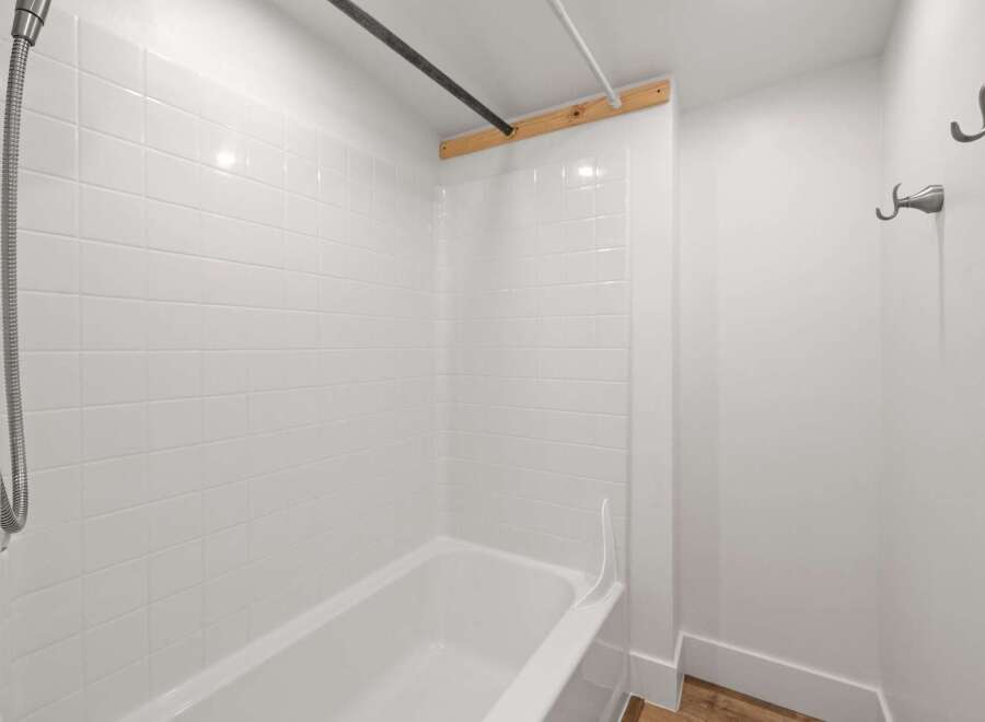 This bathroom features a pristine white tiled shower and bathtub, offering a clean and bright aesthetic.