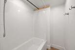 This bathroom features a pristine white tiled shower and bathtub, offering a clean and bright aesthetic.