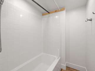 This bathroom features a pristine white tiled shower and bathtub, offering a clean and bright aesthetic.