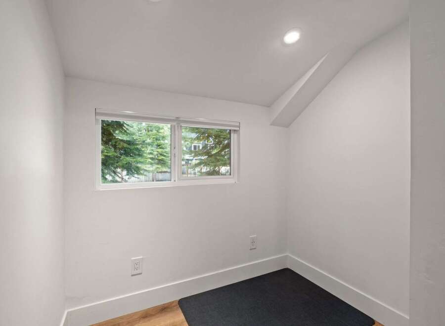 This bright and airy room features a large window offering picturesque views of lush green trees.