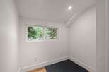 This bright and airy room features a large window offering picturesque views of lush green trees.