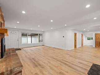 Step into this beautifully renovated living space featuring a stunning brick fireplace and a large picture window that floods the room with natural light.