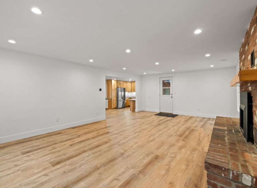 This spacious open-concept living area features a stunning brick fireplace and beautiful light wood-look flooring.