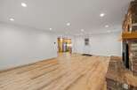 This spacious open-concept living area features a stunning brick fireplace and beautiful light wood-look flooring.