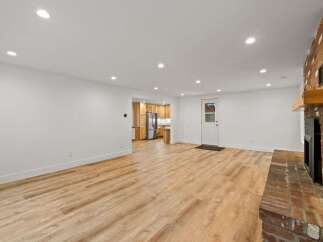This spacious open-concept living area features a stunning brick fireplace and beautiful light wood-look flooring.