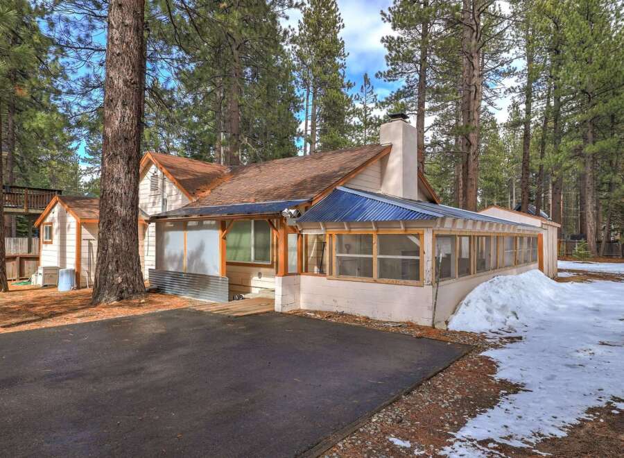 Nestled among tall pine trees, this charming home offers a unique screened-in porch perfect for enjoying the crisp mountain air.