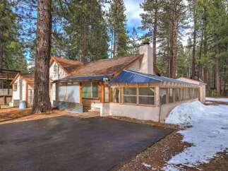 Nestled among tall pine trees, this charming home offers a unique screened-in porch perfect for enjoying the crisp mountain air.