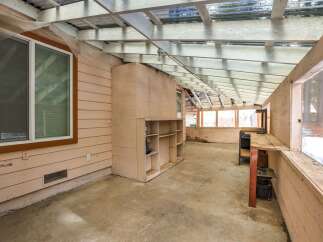 Discover the potential of this versatile sunroom, perfect for a workshop or greenhouse.