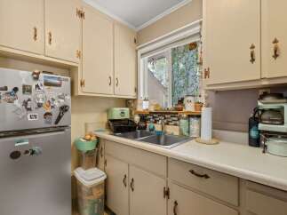 This charming kitchen features a double sink beneath a window with decorative curtains, offering a bright and airy feel.
