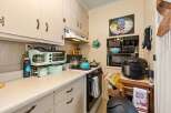 Discover this charming kitchen, perfect for home chefs! It features a compact gas stove with a blue kettle and pots, a retro-style coffee maker and toaster oven, and ample counter space for meal prep.