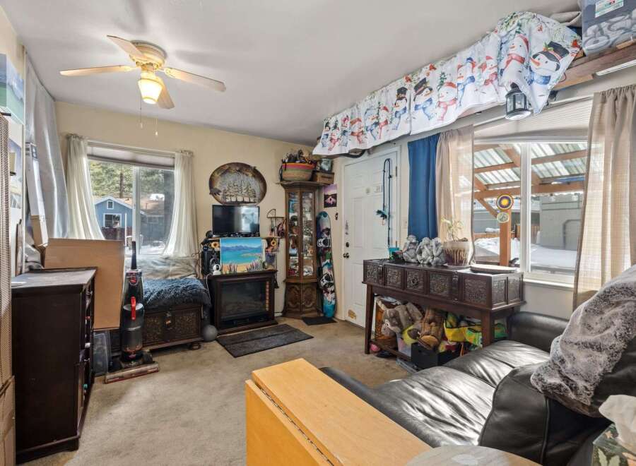Cozy living room featuring a fireplace, a ceiling fan, and ample storage solutions.