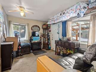 Cozy living room featuring a fireplace, a ceiling fan, and ample storage solutions.