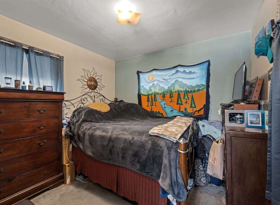 Discover a cozy bedroom featuring a comfortable bed adorned with a plush grey blanket and decorative pillows.