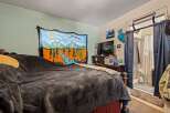 This cozy bedroom features a comfortable bed adorned with plush blankets and a vibrant tapestry depicting a serene river landscape.