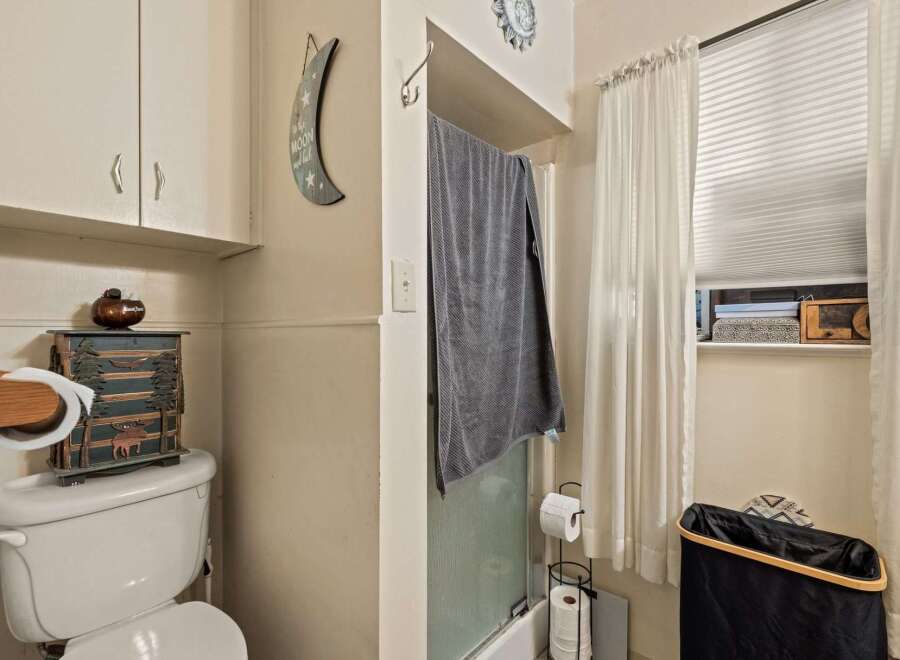 This charming bathroom features a functional toilet with a decorative storage cabinet and a wall-mounted toilet paper holder.