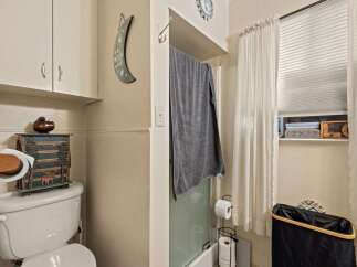This charming bathroom features a functional toilet with a decorative storage cabinet and a wall-mounted toilet paper holder.