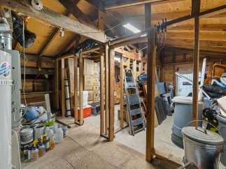 This spacious storage area offers ample room for all your belongings, featuring a water heater and a variety of paint and cleaning supplies.