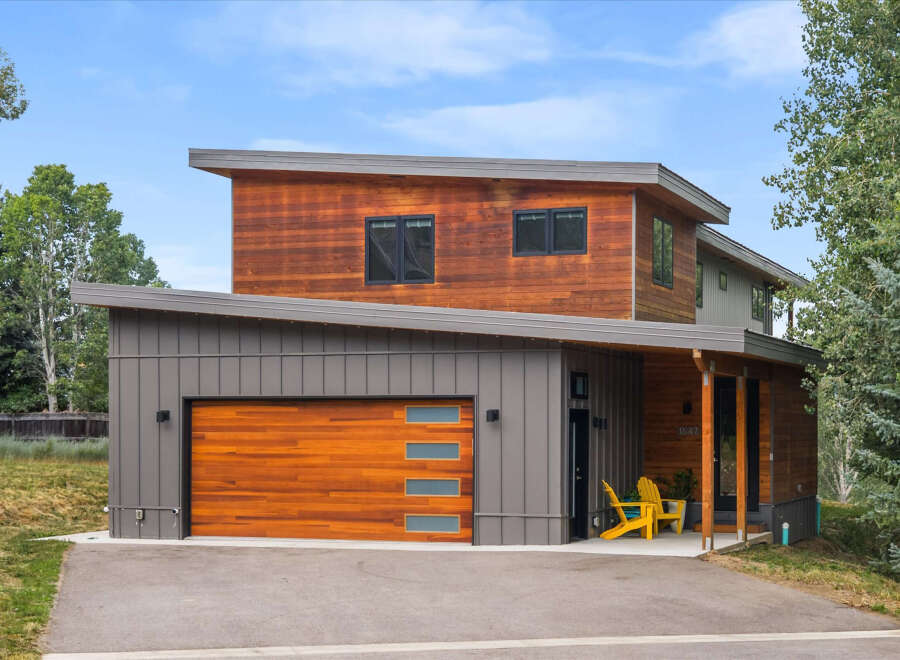Discover modern living in this stunning home featuring a striking combination of warm wood and sleek gray siding.