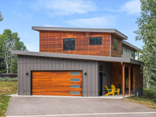Discover modern living in this stunning home featuring a striking combination of warm wood and sleek gray siding.