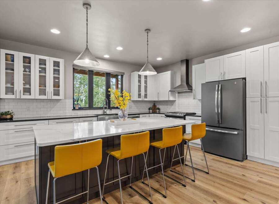 Experience modern luxury in this stunning kitchen, featuring sleek white cabinetry, a spacious quartz island with seating, and a professional-grade stainless steel range hood.