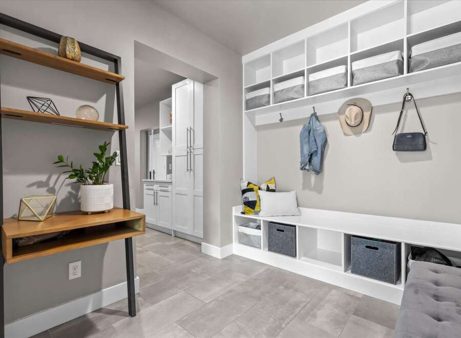 This modern entryway features a built-in white bench with ample storage, perfect for organizing shoes and accessories.