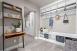 This modern entryway features a built-in white bench with ample storage, perfect for organizing shoes and accessories.