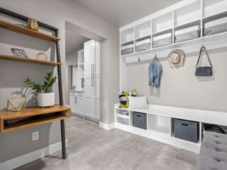 This modern entryway features a built-in white bench with ample storage, perfect for organizing shoes and accessories.