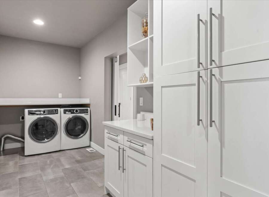 Discover this modern laundry room featuring sleek white cabinetry and a spacious countertop.