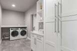 Discover this modern laundry room featuring sleek white cabinetry and a spacious countertop.