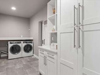 Discover this modern laundry room featuring sleek white cabinetry and a spacious countertop.