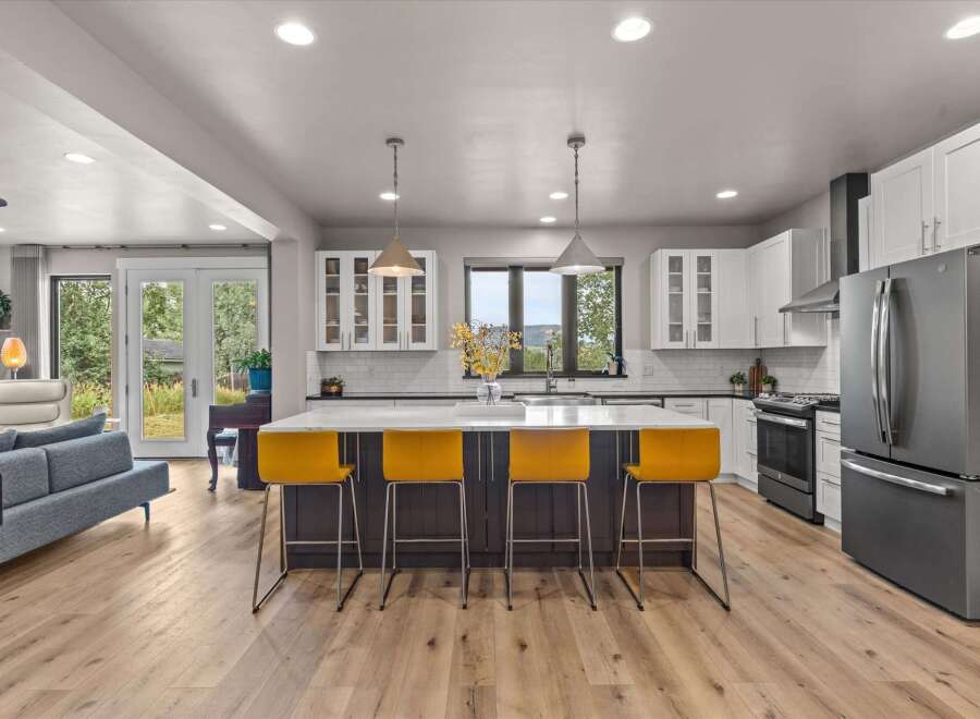 Experience modern living in this stunning open-concept kitchen, featuring a large island with vibrant yellow bar stools perfect for casual dining or entertaining.