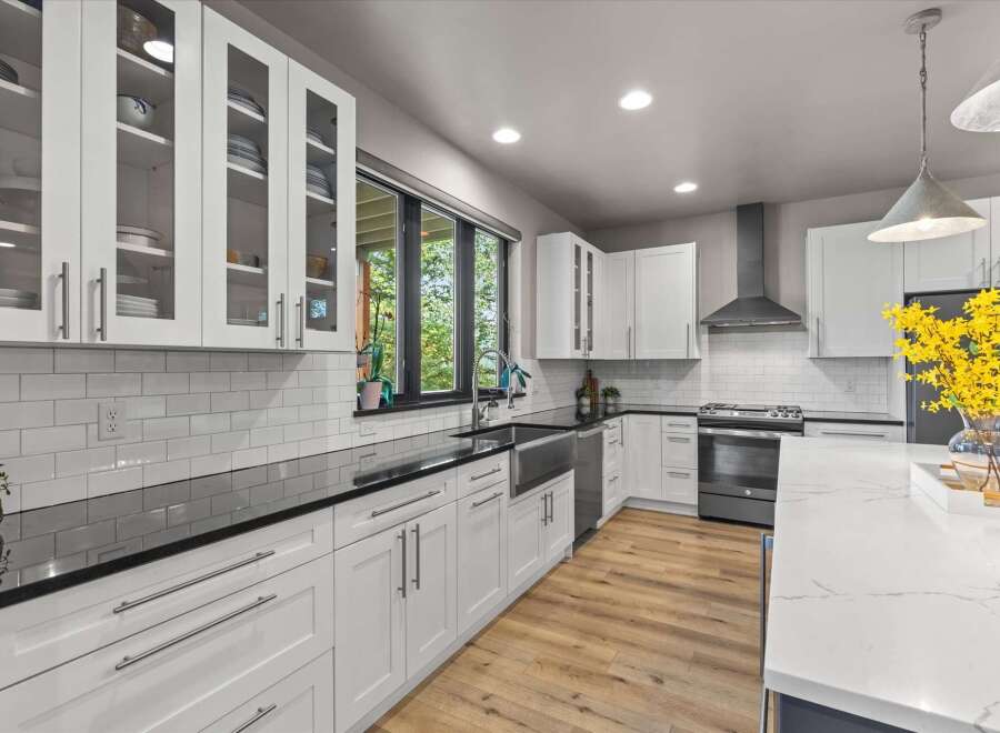 Experience modern living in this stunning kitchen featuring sleek white cabinetry, elegant black countertops, and a beautiful subway tile backsplash.